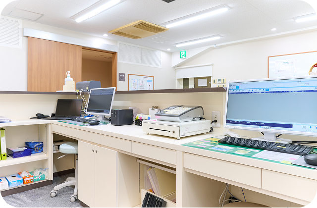 受付カウンター裏の写真。PC等の各種機器が置かれています。